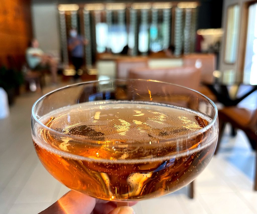 Hand holding a coupe glass of sparkling rosé wine